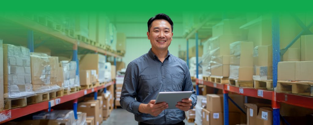 Chinese Malaysian shop owner checking stock in a small warehouse with boxes neatly arranged – SiteGiant inventory management Malaysia